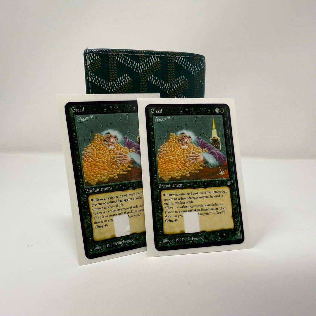 Set of two identical Greed Magic: The Gathering credit card stickers displayed side by side against green patterned wallet, showing classic MTG enchantment artwork with golden treasure pile and black border design from Kibakiba.co